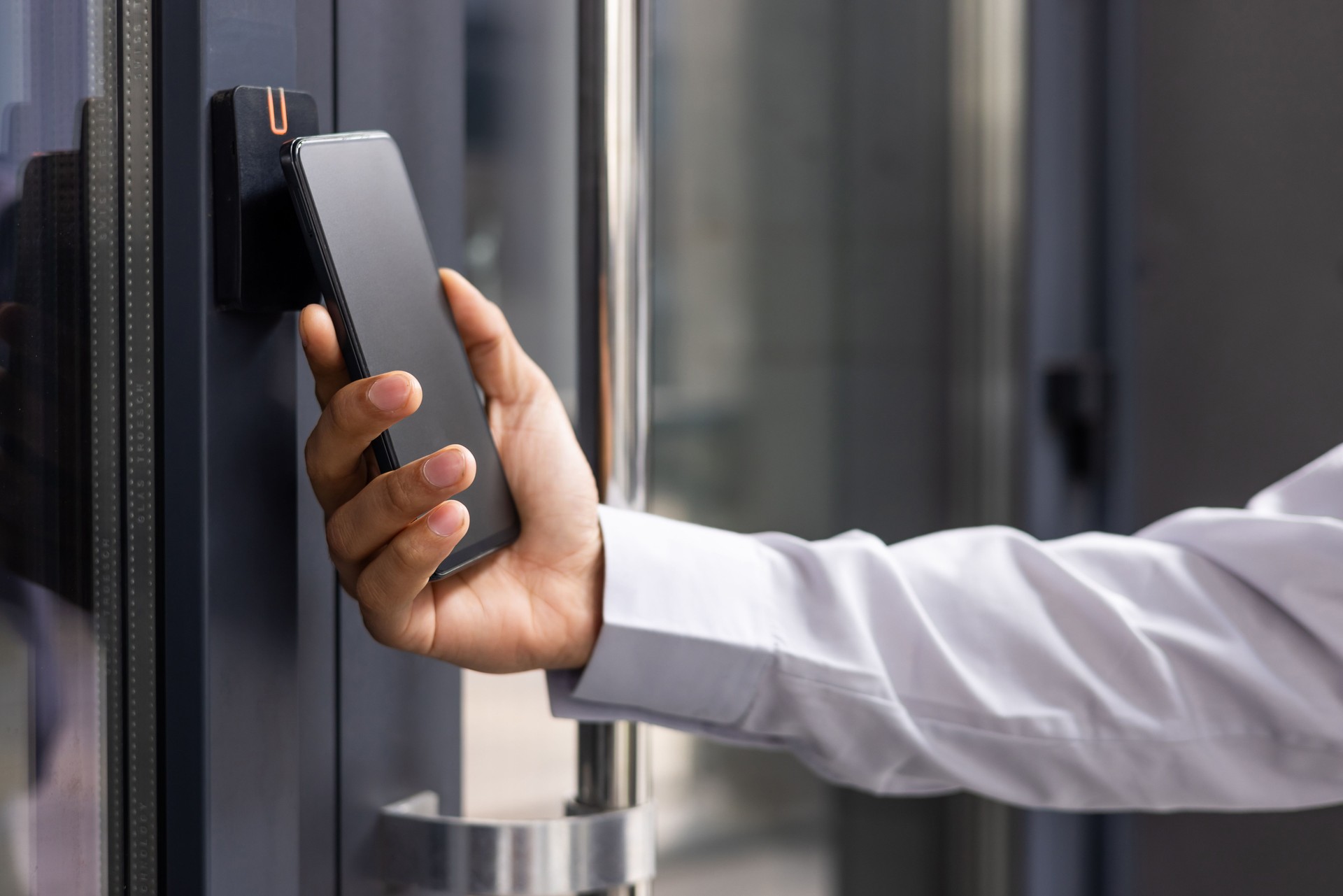 Hand man closely with the phone, the businessman uses the application on the smartphone to remove the door opening of the house, office